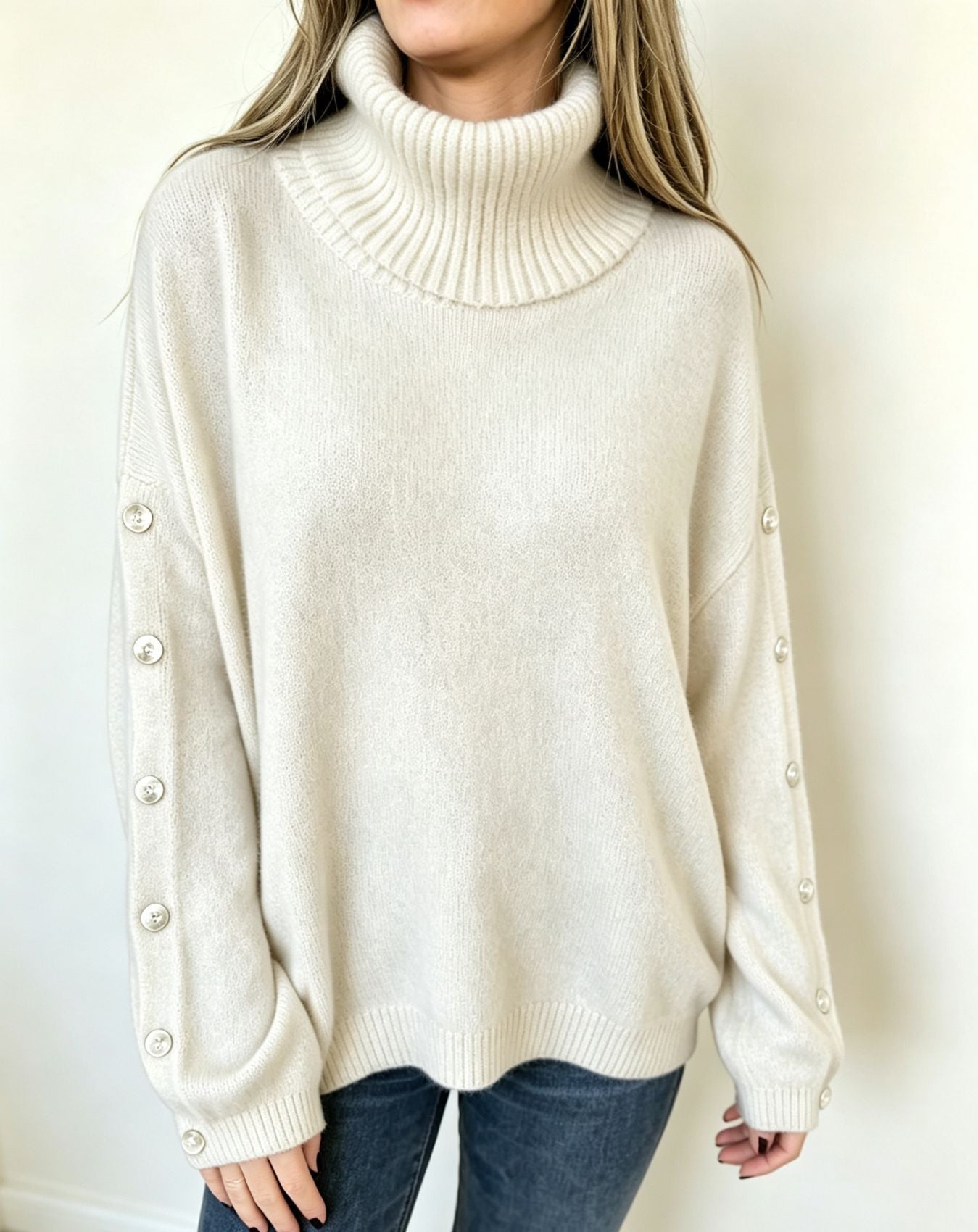 Oversized white knit turtleneck pullover with buttoned cuffs, long sleeves