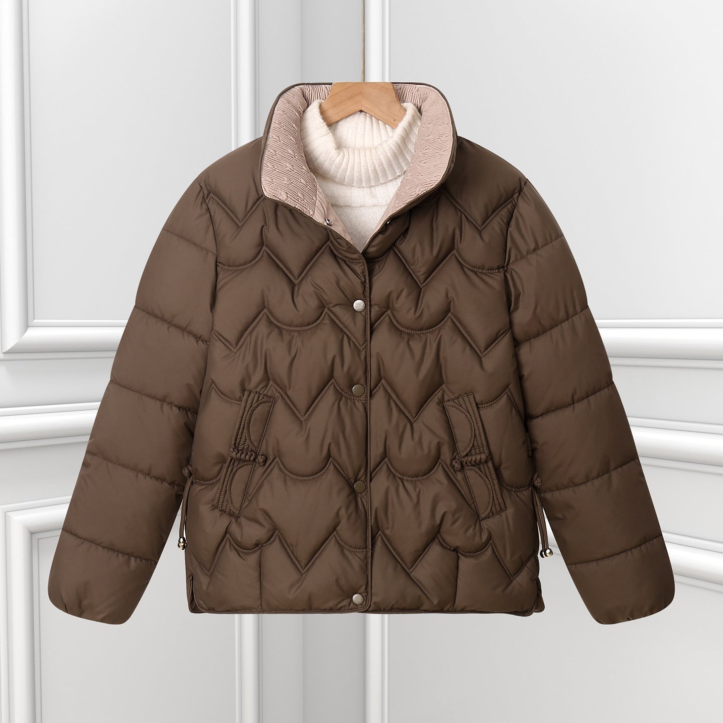 Brown short quilted puffer jacket with curved stitching and snap-button front