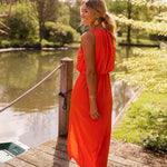 Orange sleeveless midi dress with front slit and gathered neckline, back toward water