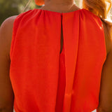 Back view of orange sleeveless midi dress with keyhole opening and gathered shoulders