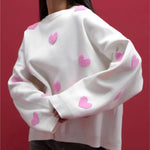 White soft pullover sweater with pink heart pattern and ribbed cuffs, crew neck.