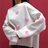 White soft pullover sweater with pink heart pattern and ribbed cuffs, crew neck.