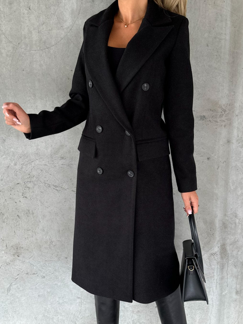 Black double-breasted overcoat with notch lapels, long sleeves, and large button details