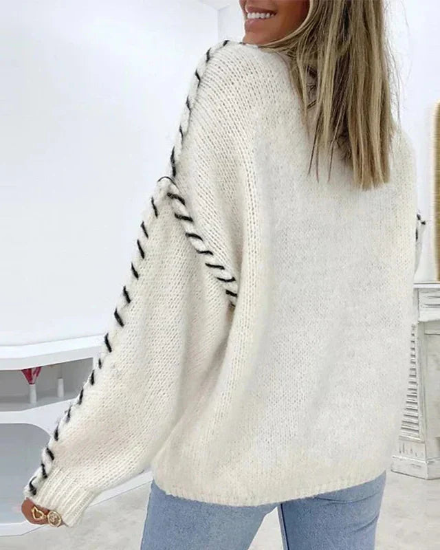 Cream knit pullover with crew neck and contrast stitched raglan-style sleeves