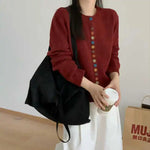 Burgundy knit cardigan with long sleeves and front button placket featuring multicolor buttons