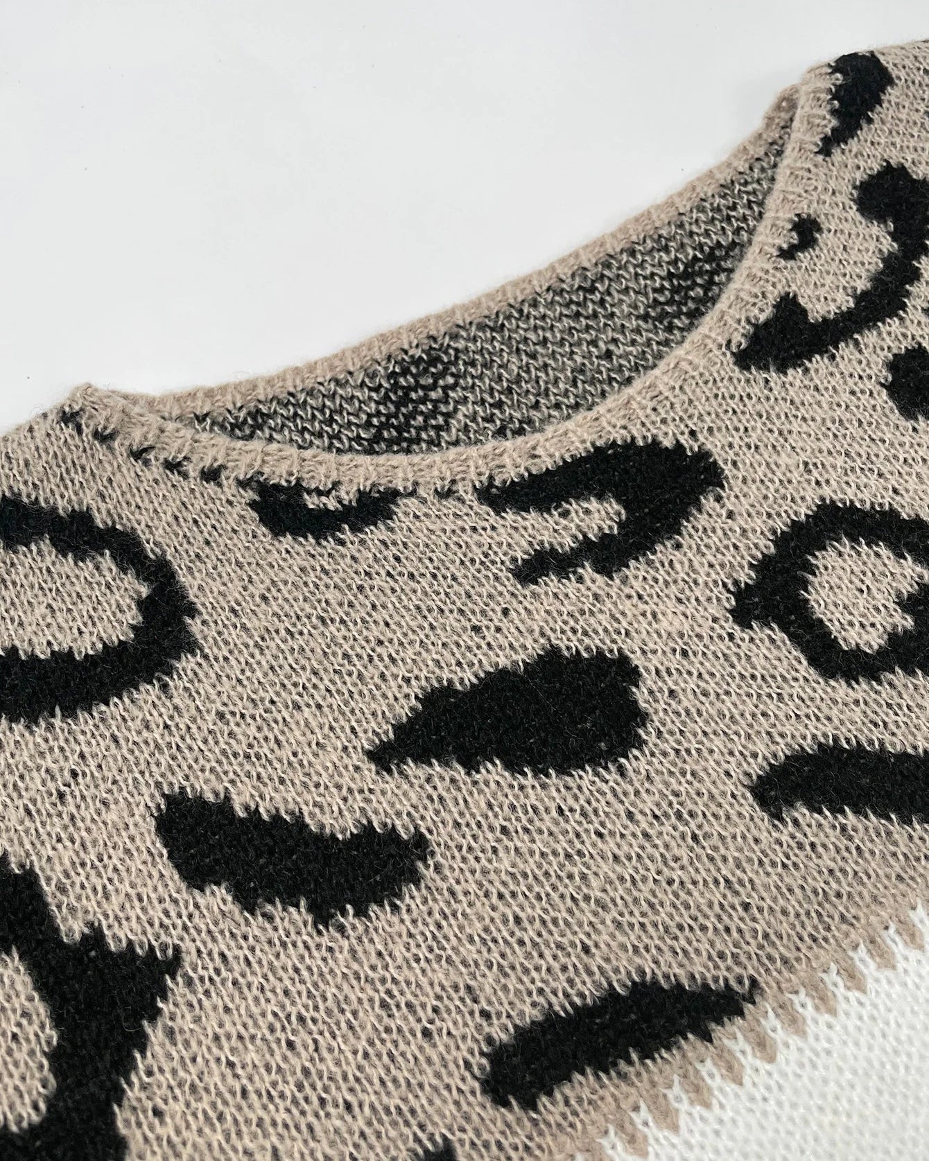 Leopard-pattern knit pullover with cream base and black spots at the neckline