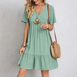 Light green V-neck tiered midi dress with short sleeves and gathered skirt
