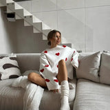 White soft pullover sweater with red heart motif, loose fit and ribbed cuffs.