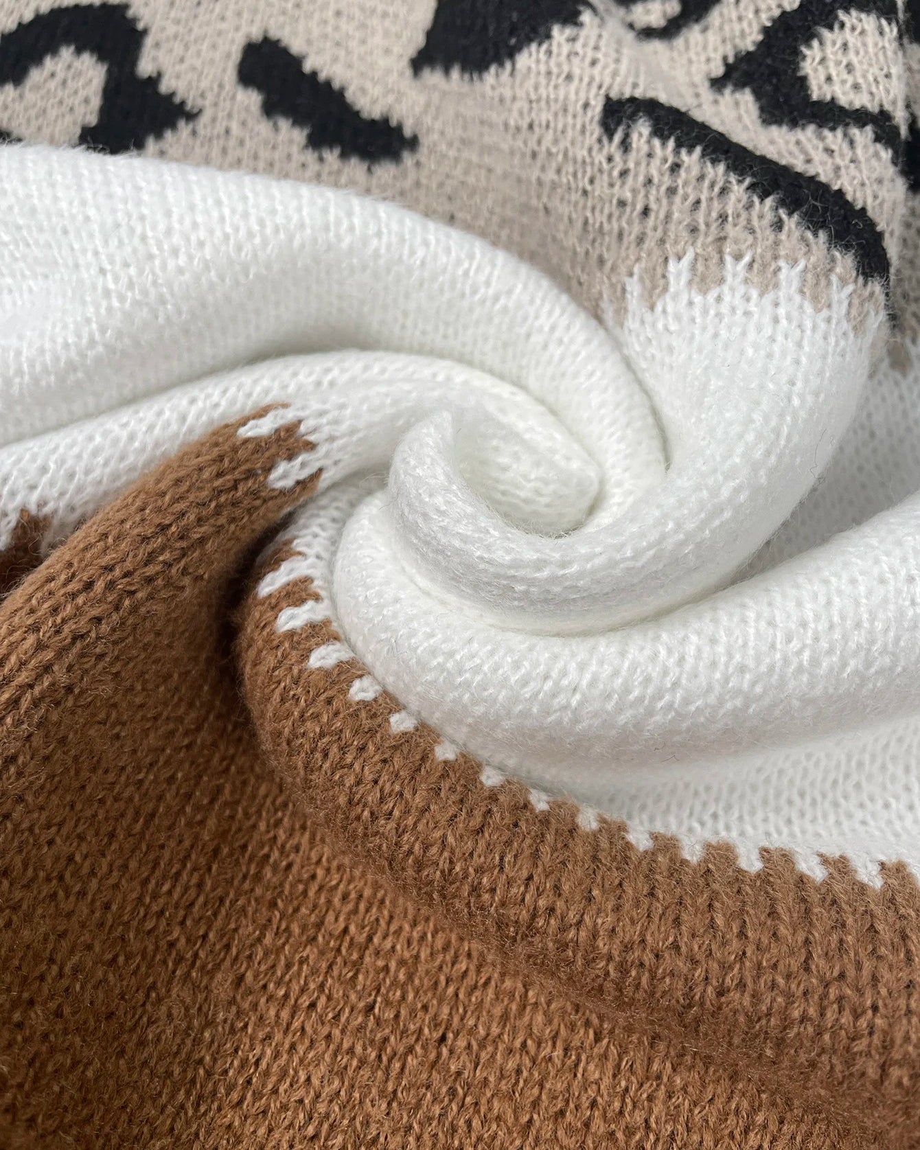Knit close-up of colorblock pullover: white and brown with contrast zigzag trim