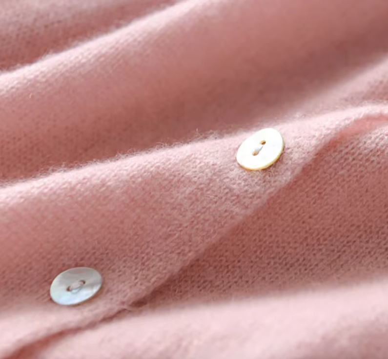 Dusty pink knit fabric close-up with round button and stitching