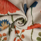 Cream knit cardigan fabric close-up with zipper seam and orange-blue floral pattern