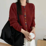 Burgundy knit cardigan with long sleeves and front button placket of multicolor buttons