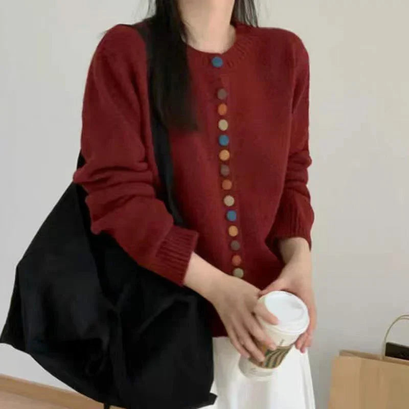 Burgundy knit cardigan with long sleeves and front button placket of multicolor buttons
