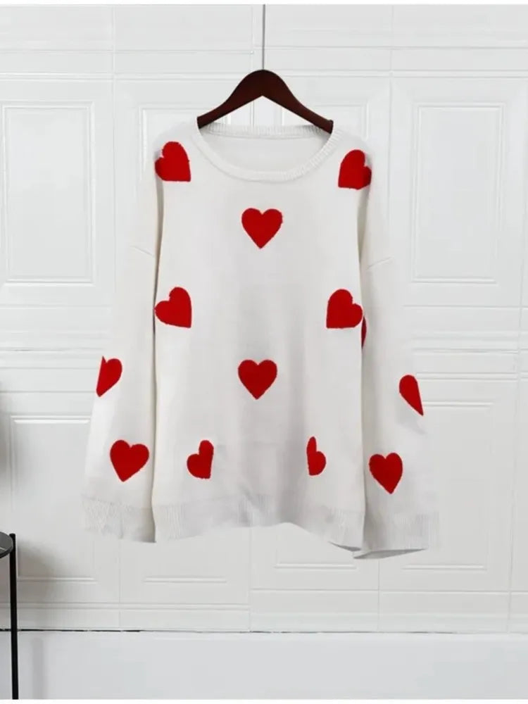 White knit pullover sweater with scattered red heart motifs, crew neck and ribbed cuffs.