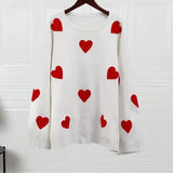 White knit pullover sweater with scattered red heart motifs, crew neck and ribbed cuffs.