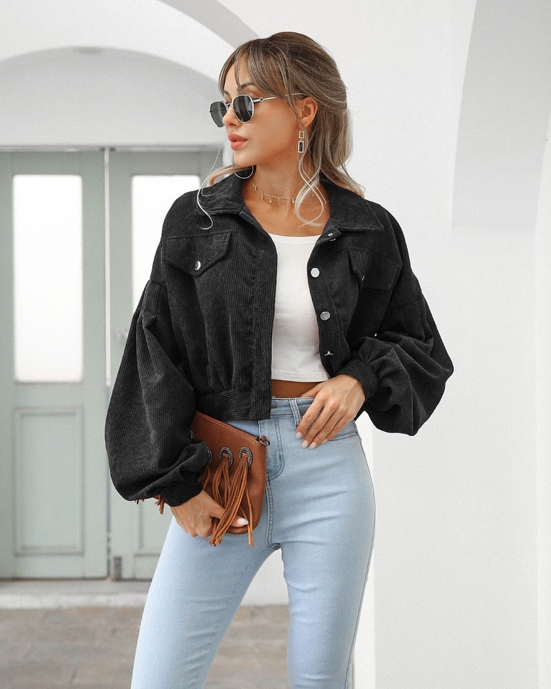 Black cropped jacket with flap pockets, button front, and long puff sleeves