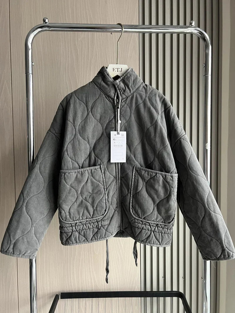 Dark gray cropped quilted jacket with full zip, flap pockets, and drawstring hem