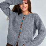 Gray knit cardigan with vertical row of multicolor round buttons and long sleeves