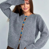Gray knit cardigan with vertical row of multicolor round buttons and long sleeves