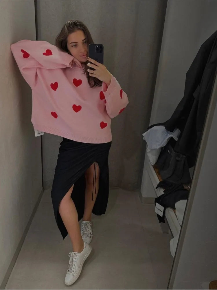 Light pink soft pullover sweater with red heart pattern, long sleeves and crew neck.