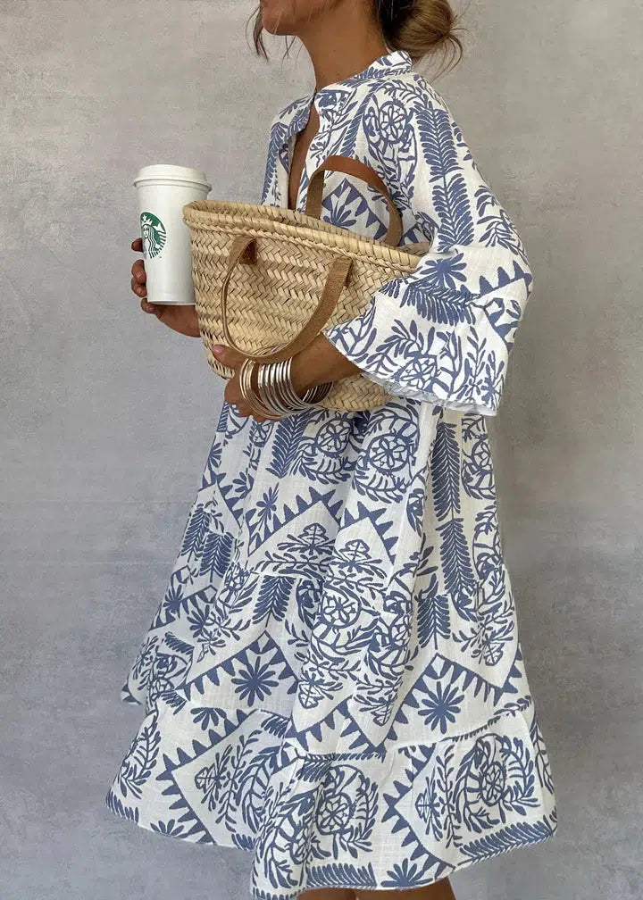 Blue-and-white patterned V-neck mini dress with long sleeves and tiered flared skirt.