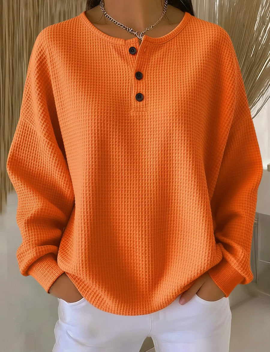 Orange waffle-knit pullover with rounded collar, button placket, and long sleeves