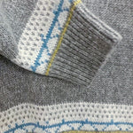 Gray sweater sleeve cuff with blue-and-white fair isle trim and striped band
