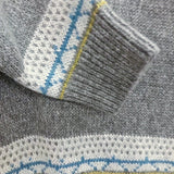 Gray sweater sleeve cuff with blue-and-white fair isle trim and striped band