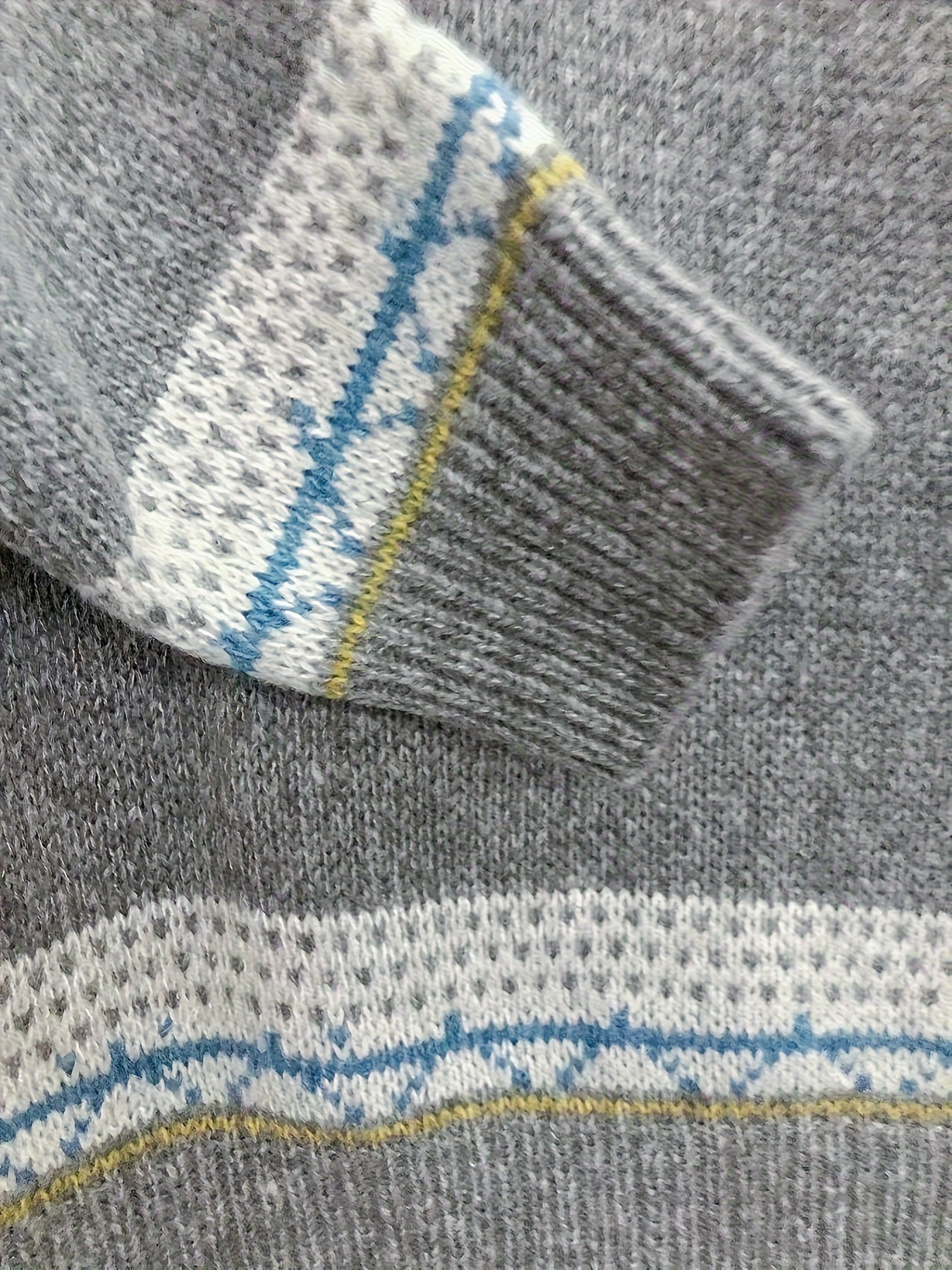 Gray sweater sleeve cuff with blue-and-white fair isle trim and striped band