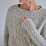 Speckled knit sweater detail with textured stitch, ribbed collar and cuffs