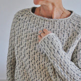 Speckled knit sweater detail with textured stitch, ribbed collar and cuffs
