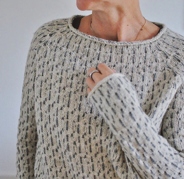 Speckled knit sweater detail with textured stitch, ribbed collar and cuffs