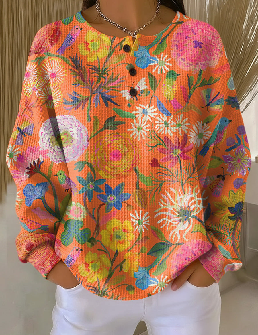 Orange floral print pullover sweater with long sleeves and henley button placket