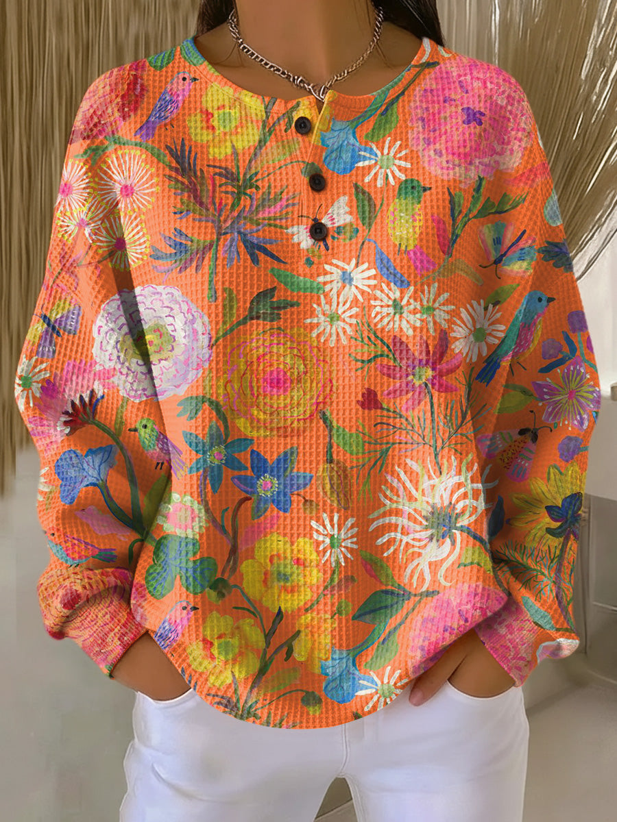 Orange floral print pullover sweater with long sleeves and henley button placket