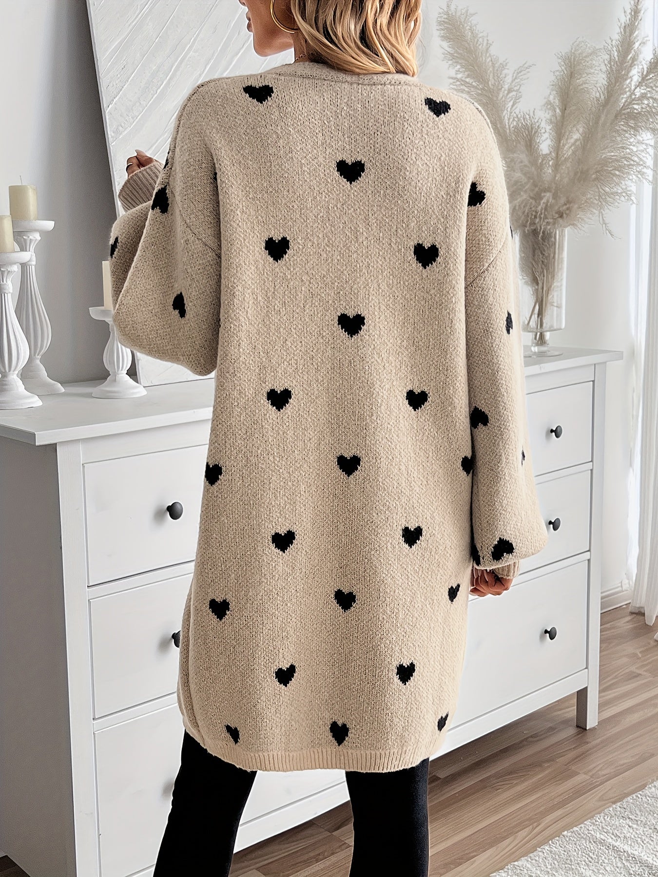 Back view of heart-pattern knit cardigan, long sleeves, light beige knit with dark hearts.