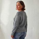 Gray knit crewneck sweater with long sleeves; side view of ribbed cuffs and hem