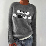 Gray knit crewneck sweater with white/black chest motif; ribbed cuffs visible