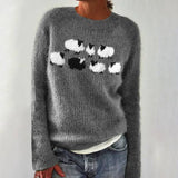 Gray knit crewneck sweater with white/black chest motif; ribbed cuffs visible