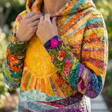 Colorful sunrise hoodie close-up with embroidered sun and floral patchwork sleeves