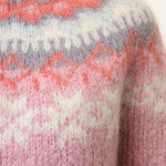 Light pink knit sweater close-up with orange and white fair isle zigzag yoke