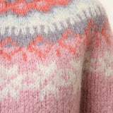 Light pink knit sweater close-up with orange and white fair isle zigzag yoke