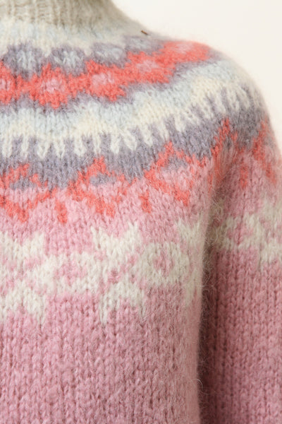 Light pink knit sweater close-up with orange and white fair isle zigzag yoke