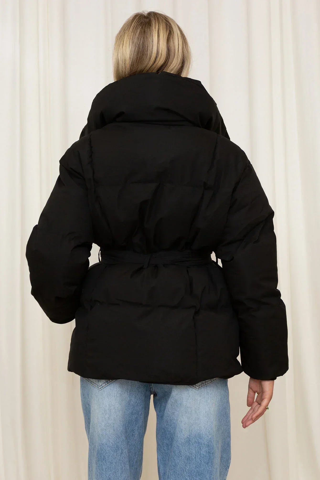 Black padded hooded jacket with tie belt, shown from the back, long sleeves.