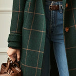 Dark green plaid coat with cuffed sleeve and front buttons, worn over blue jeans