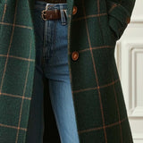 Dark green plaid coat with two front buttons and long hem, worn over blue jeans