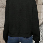 Black bomber jacket, back view, textured chevron knit and ribbed hem.