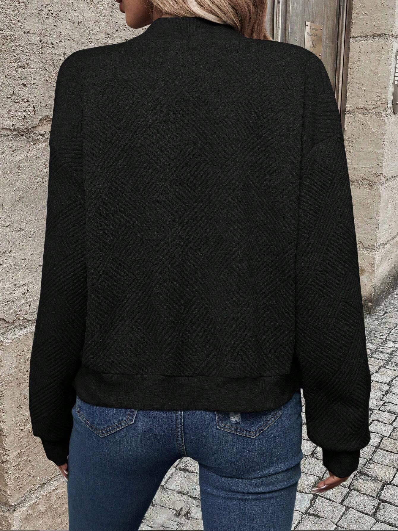 Black bomber jacket, back view, textured chevron knit and ribbed hem.